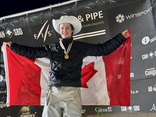 Stian on the podium wearing gold medal, Stampede hat, and Canadian flag at 2026 Junior World Championships rail event for snowboarding